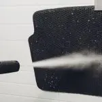 Washing my car floor mats using a power washer by my garage