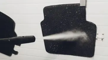 Washing my car floor mats using a power washer by my garage