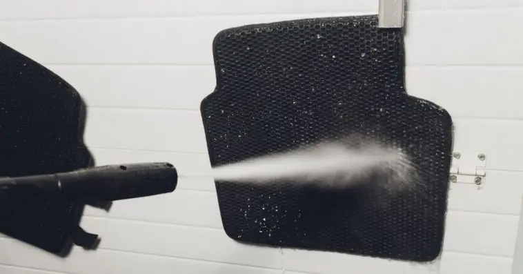 Washing my car floor mats using a power washer by my garage